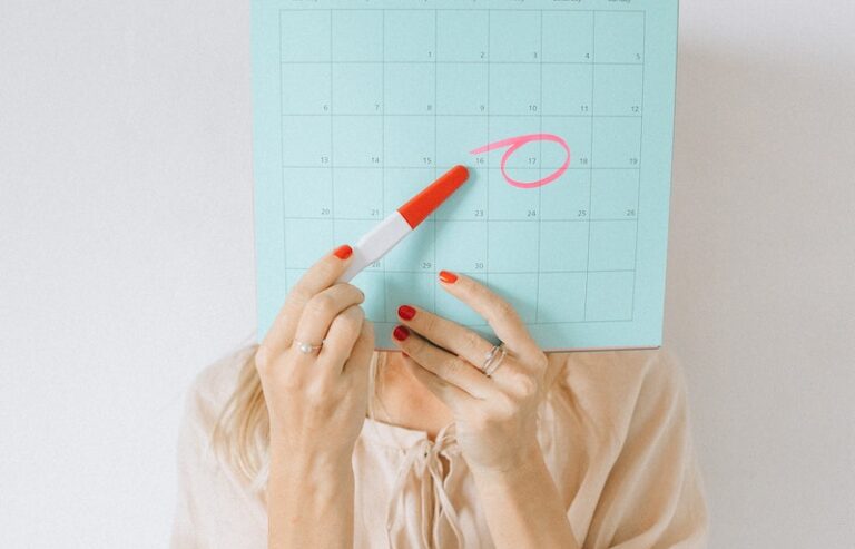 A Woman Pointing a Pregnancy Test at a Calendar