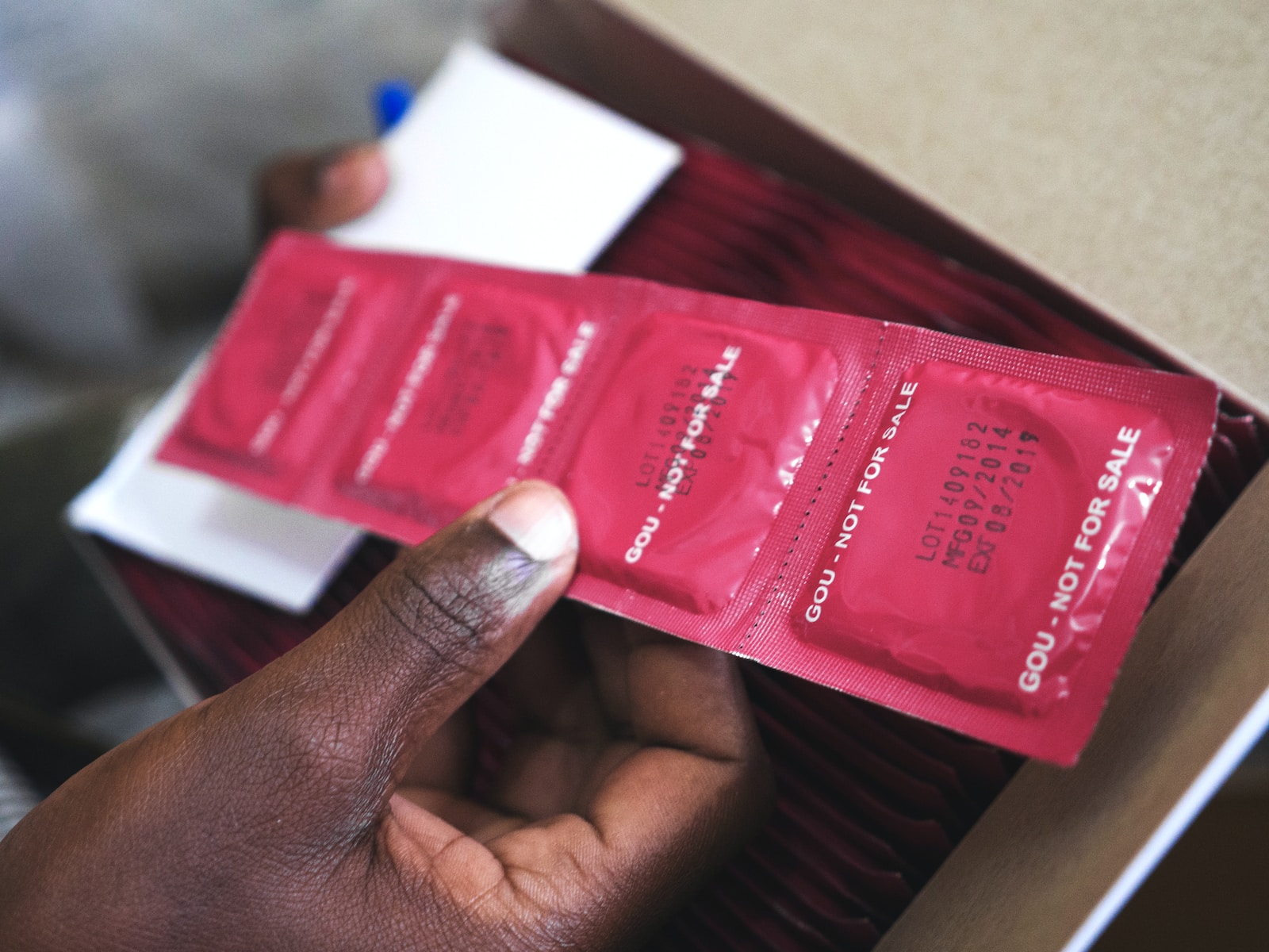 man holding red condom packs